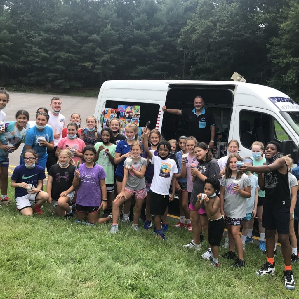 People enjoying ice cream from a colorful ice cream truck at a social event